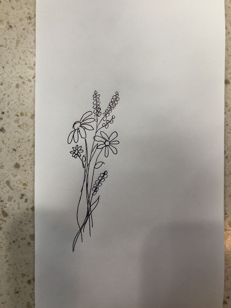 a drawing of some flowers on a piece of paper that is sitting on a table