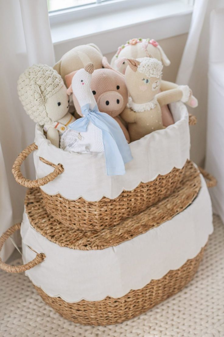 a basket filled with stuffed animals sitting on top of a floor next to a window