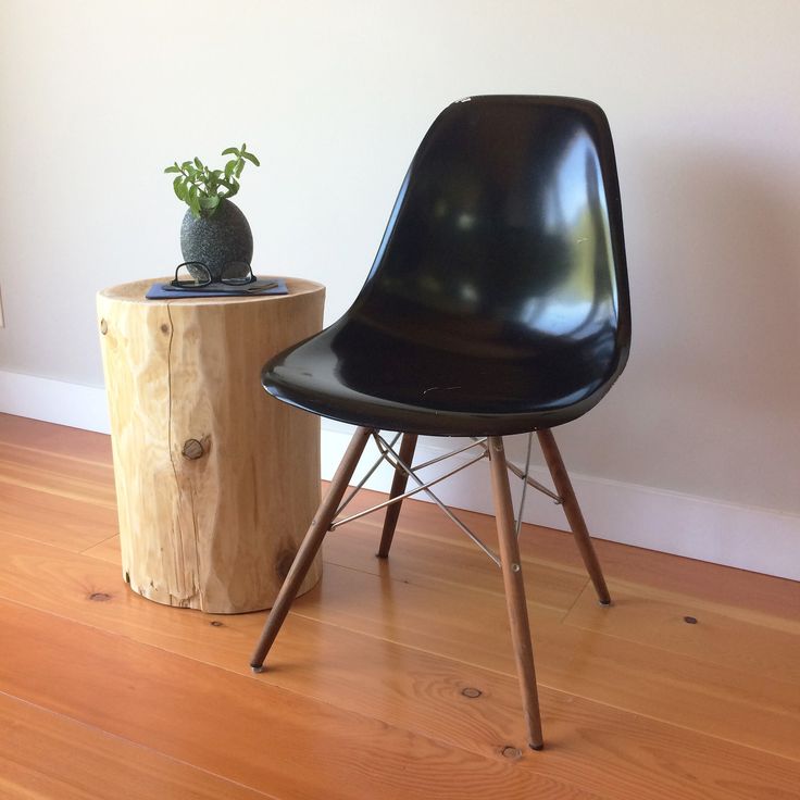 a black chair next to a wooden stump with a potted plant on top of it