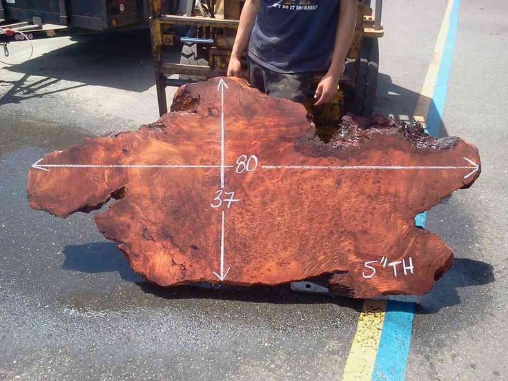 a man standing next to a large piece of wood that has been cut in half