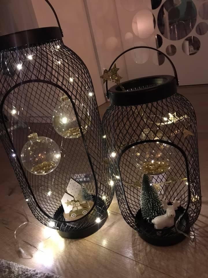 two metal lanterns with lights in them sitting on the floor next to each other,