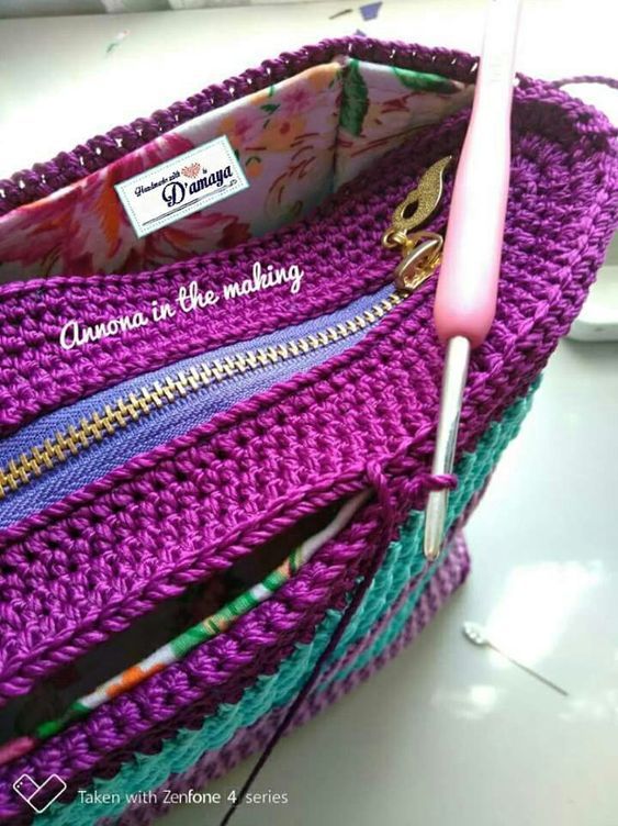 a purple crocheted purse with zippers and a pink toothbrush in it