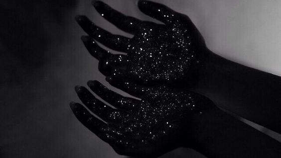 black and white photograph of two hands with glitter on them