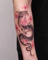 a woman's arm with a dragon tattoo on the left side of her arm