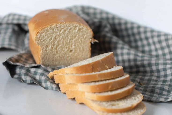 a loaf of bread sitting on top of a table next to slices of sliced bread