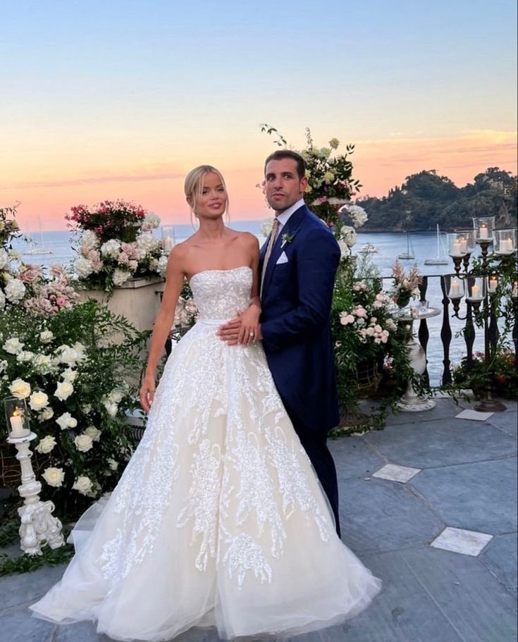 a man and woman standing next to each other in front of flowers