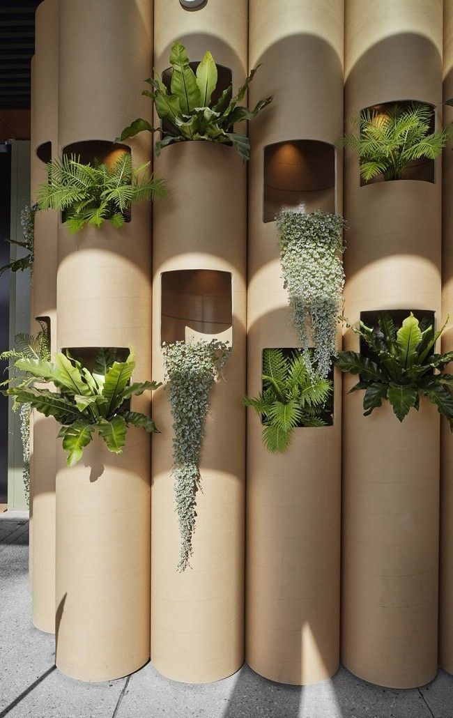 several planters are arranged on the side of a building with concrete columns and plants growing out of them