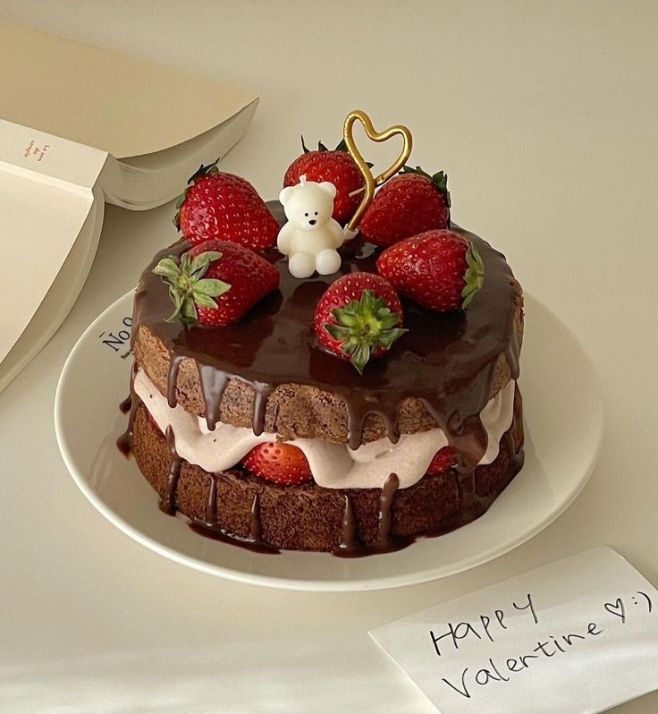 a chocolate cake topped with strawberries and a teddy bear