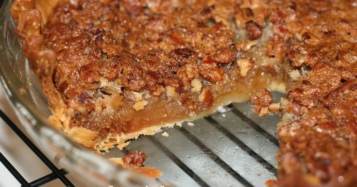 a pie sitting on top of a metal rack next to a glass pan filled with food