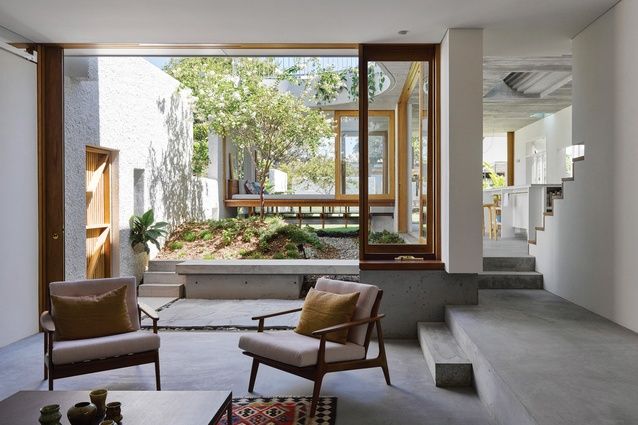 an open living room with two chairs and a table in front of large windows that look out onto the backyard