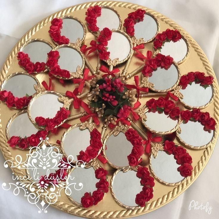 a gold plate with red flowers and mirrors on the side, sitting on a white table cloth