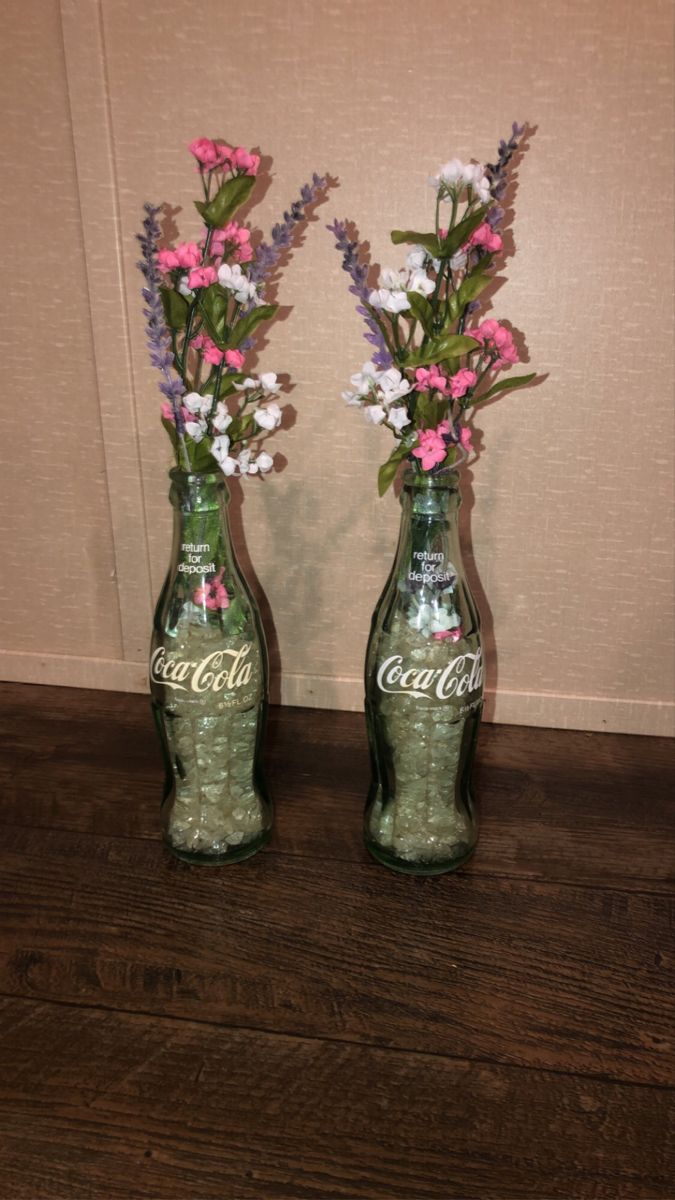 two green coke bottles with pink and white flowers in them