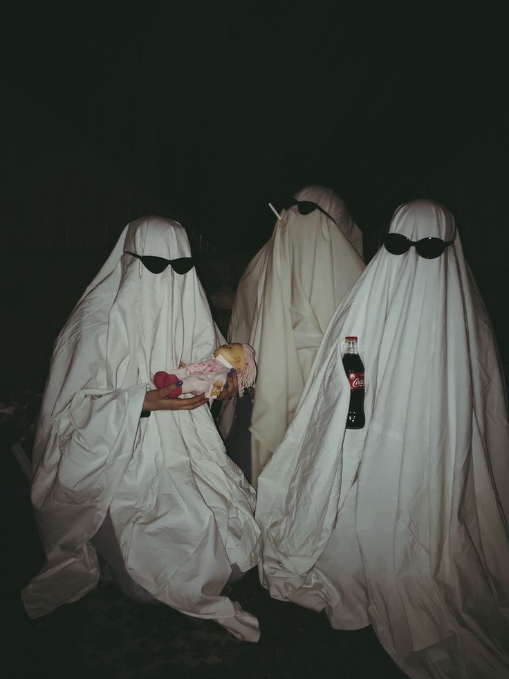 three people in white cloths with bottles and food on their backs, all covered up