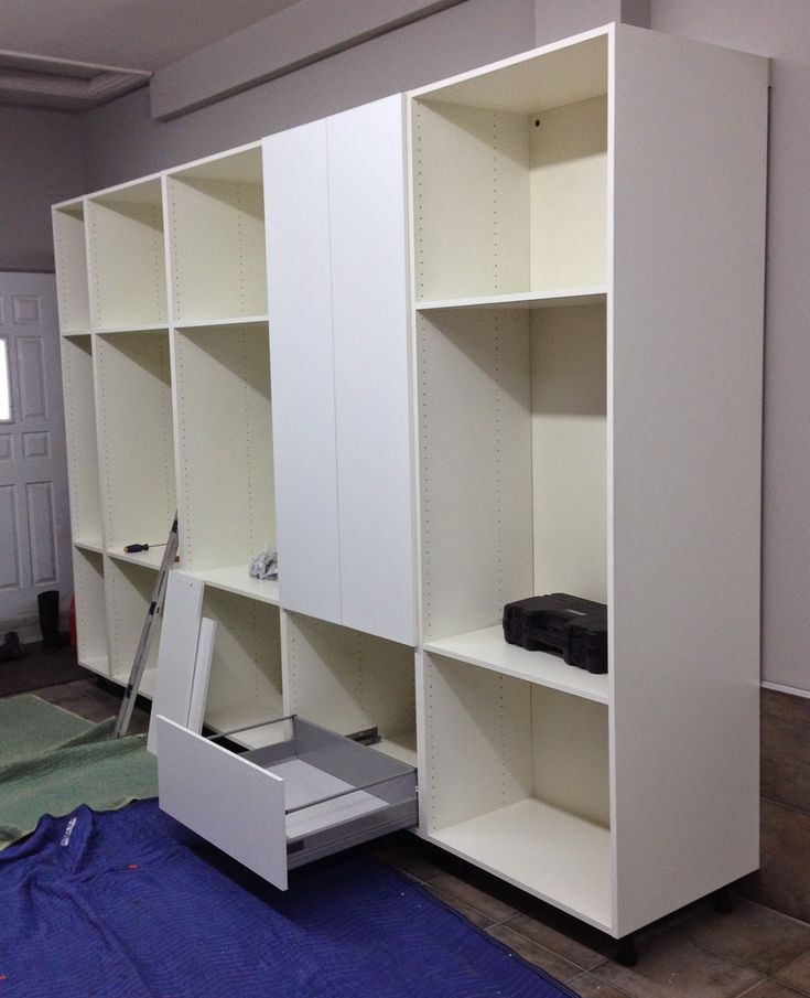 an empty room with some white shelves and drawers