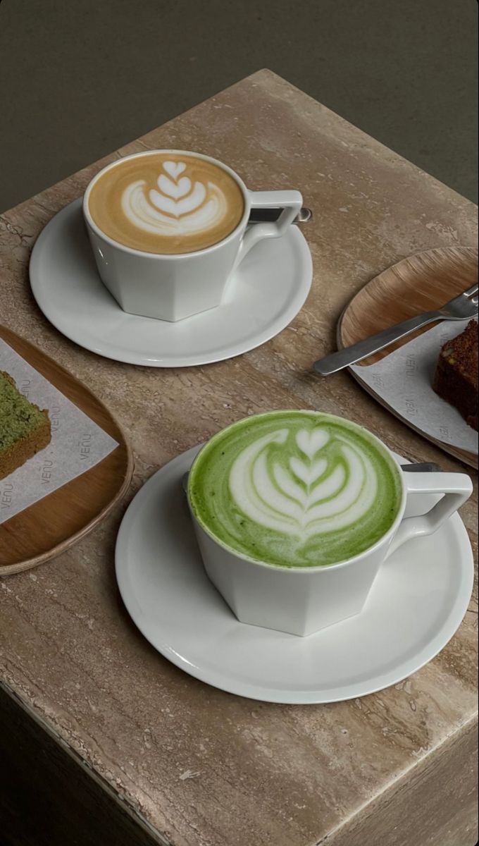 there is a cup of green tea and cake on the table next to each other