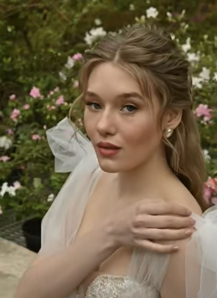 a woman in a wedding dress is posing for a photo with flowers around her neck