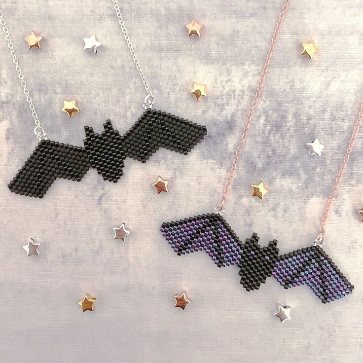 two cross stitch necklaces with the word bat on them and stars hanging from chains