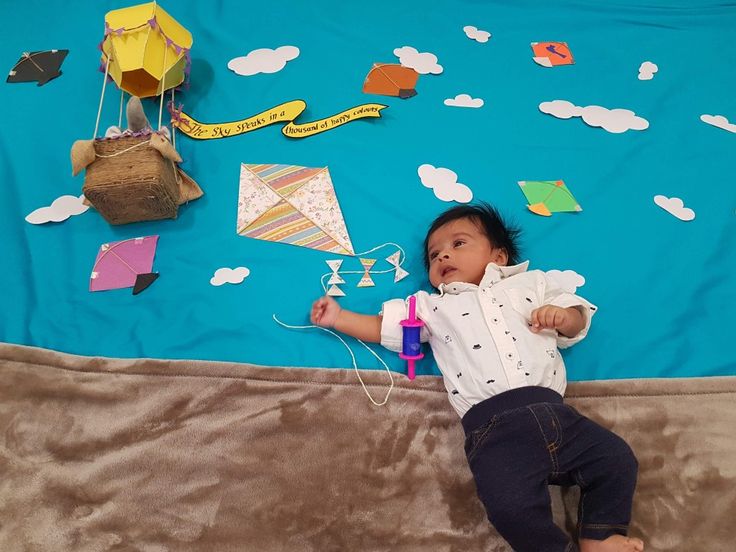 a baby is laying on the floor with kites and other items around him,