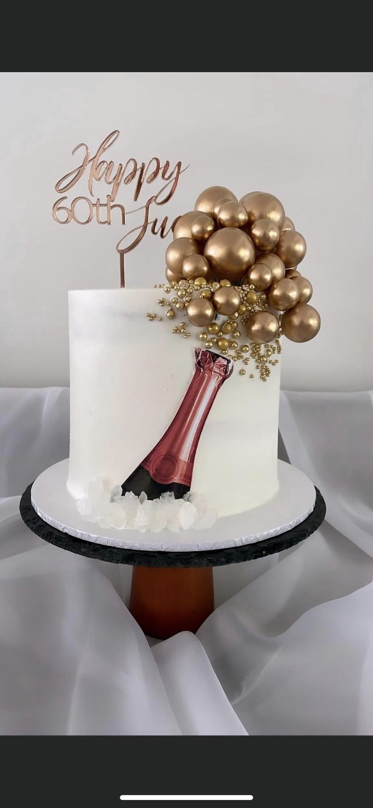 a white cake topped with gold balls and a wine bottle