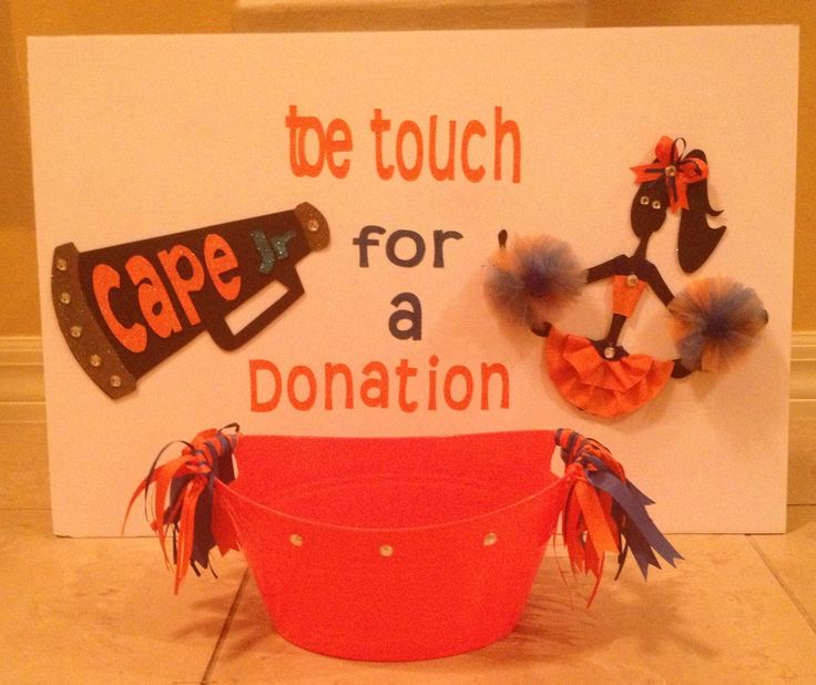 a red bucket with pom poms on it sitting in front of a sign that says cape for a donation