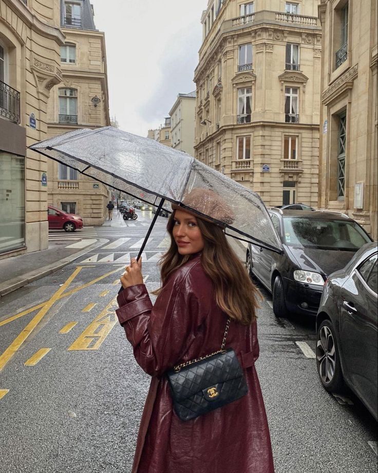 a woman is standing in the rain holding an umbrella