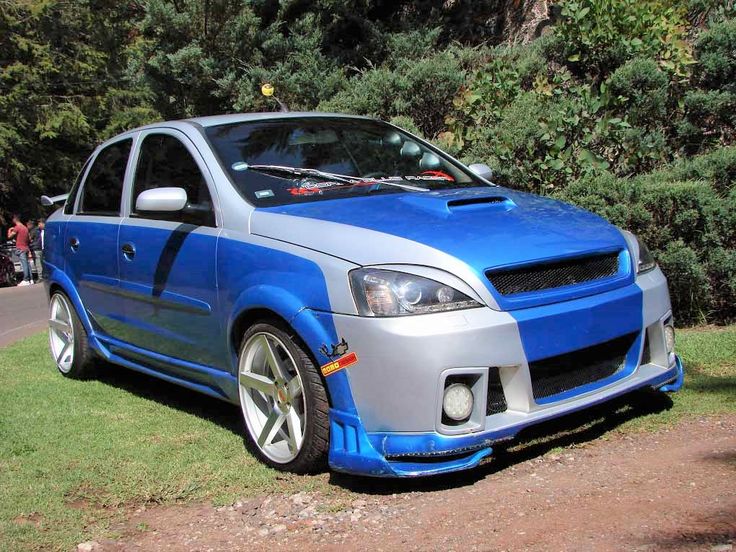 a blue and silver car parked on the side of a road next to some trees