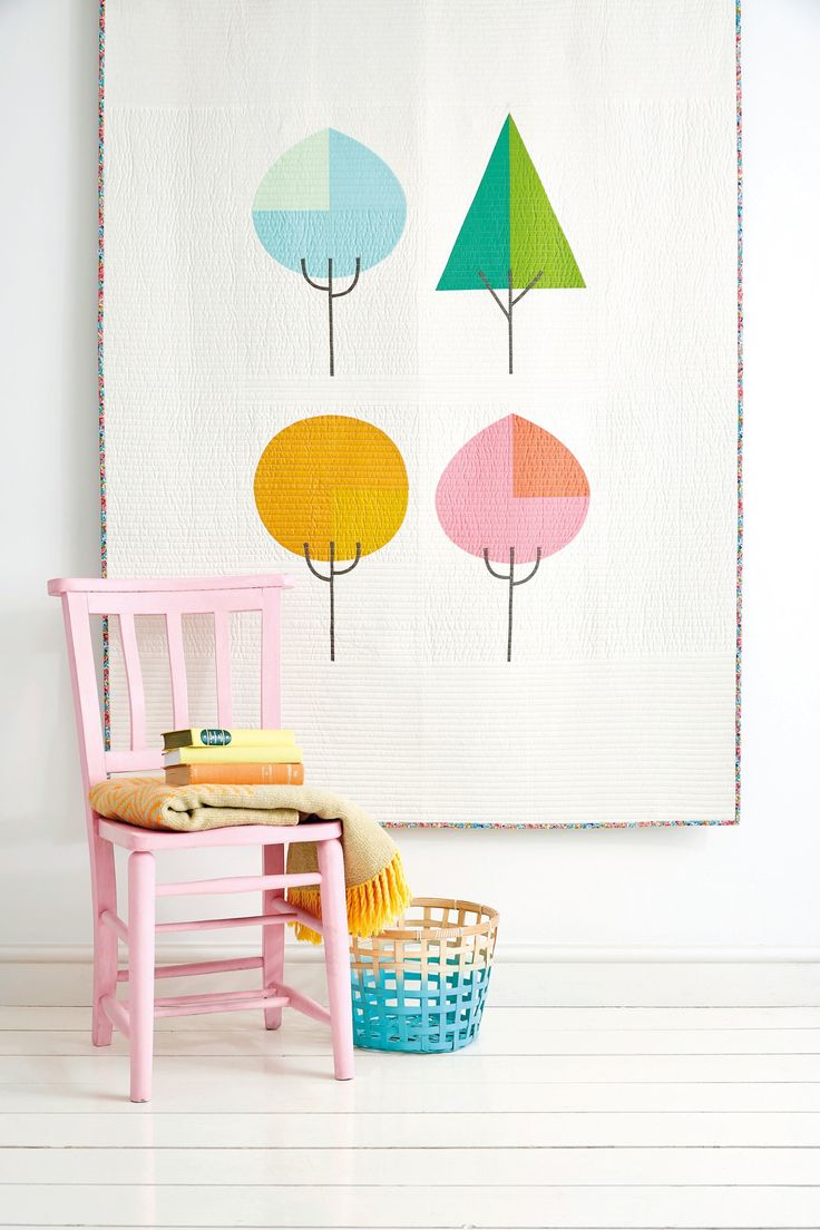 a small wooden chair sitting next to a wall hanging with trees on it's side