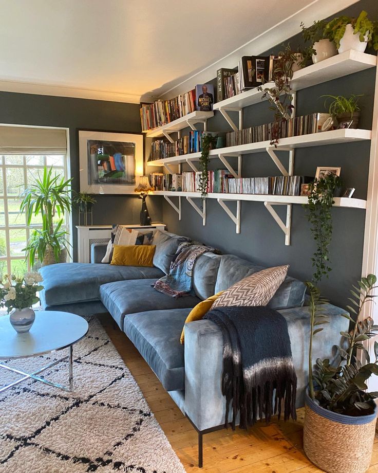 a living room filled with furniture and bookshelves on the wall next to a window