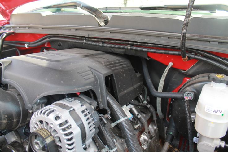 the engine compartment of a red car with its hood open and hoses attached to it