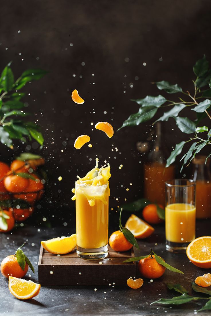 an orange juice is being poured into a glass on a cutting board surrounded by oranges