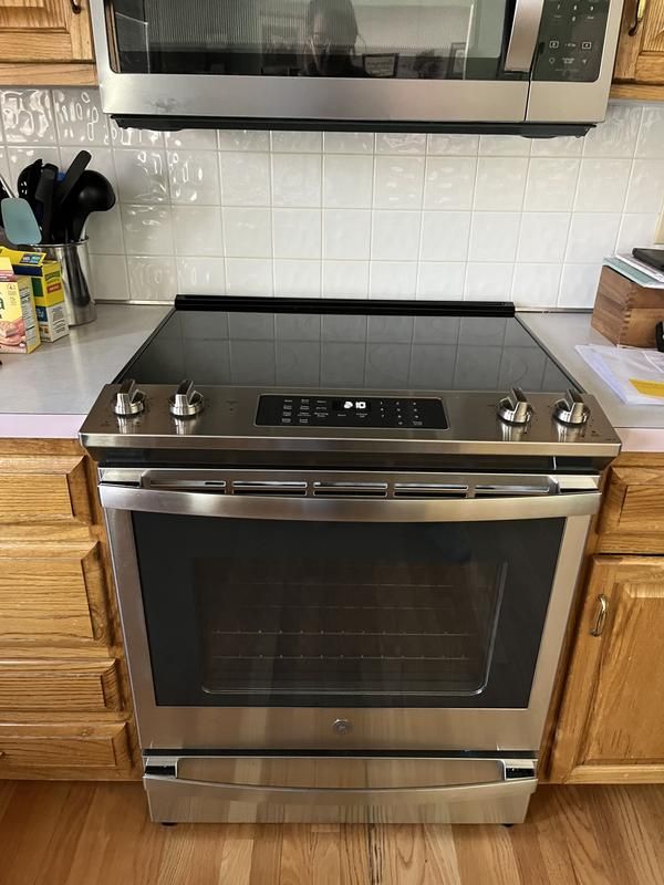 a stainless steel oven in a kitchen with wooden cabinets and white tile backsplash