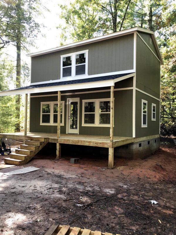 a small house in the woods with stairs leading up to it's second floor