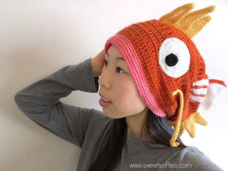 a woman wearing a knitted hat with an orange fish on it's side