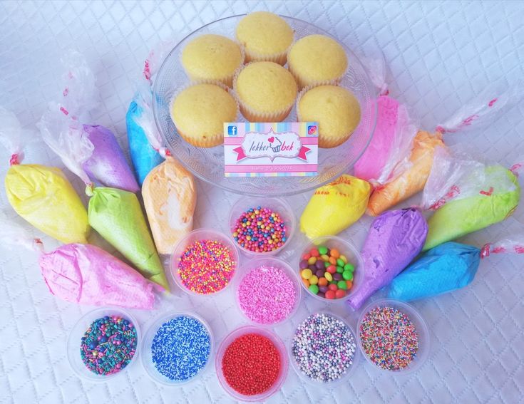 cupcakes and sprinkles in plastic containers on a white tablecloth