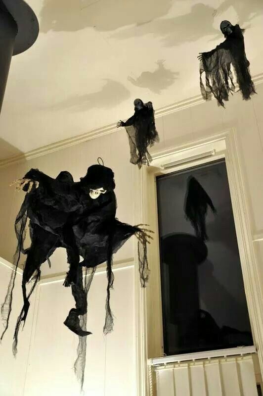 halloween decorations hanging from the ceiling in front of a window