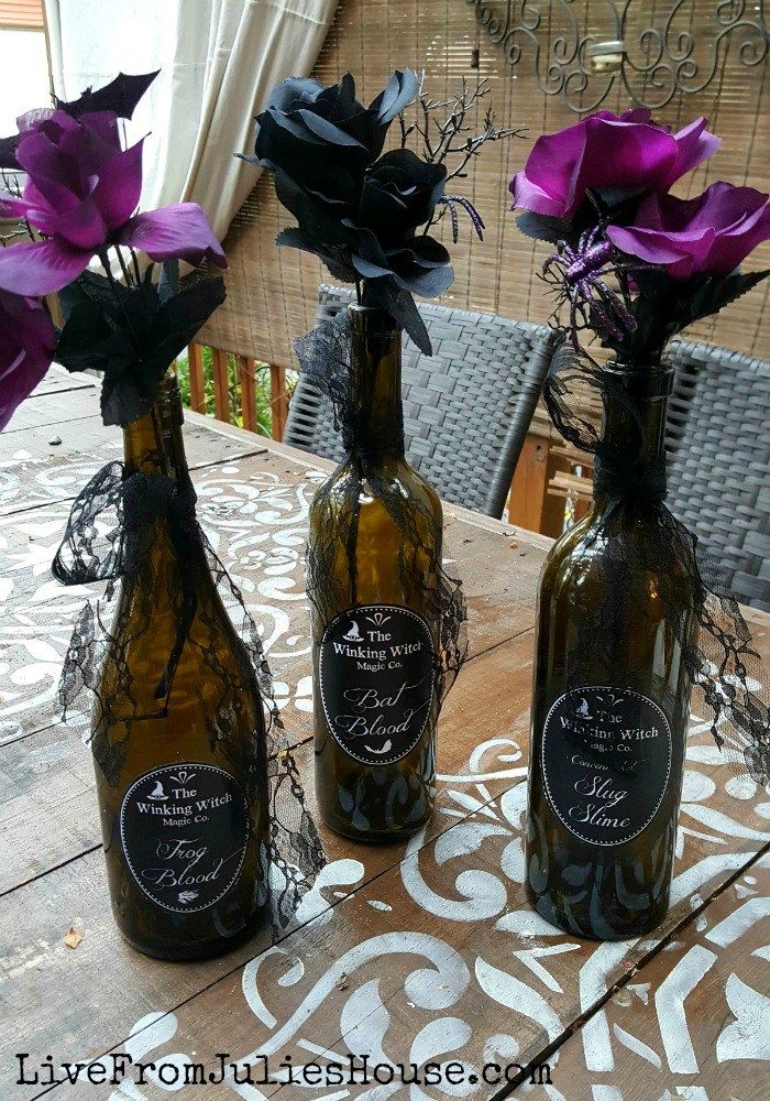 three wine bottles with flowers in them sitting on a table