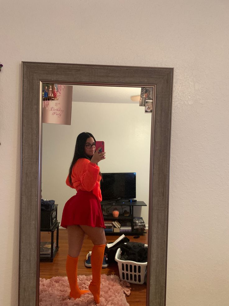 a woman taking a selfie in a mirror with her legs crossed and orange socks on