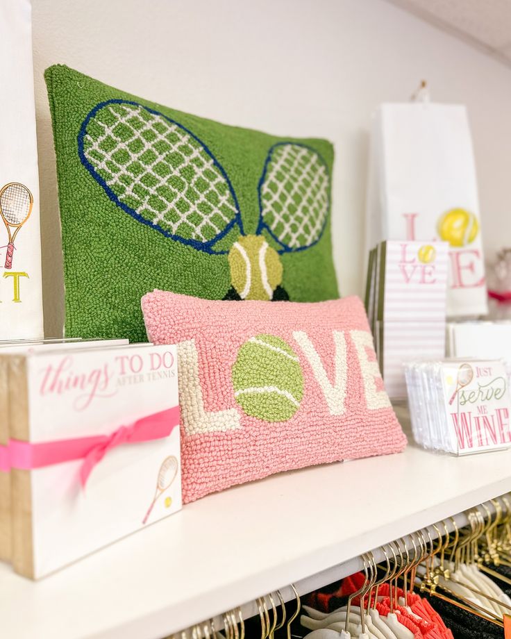 pillows and other decorative items are displayed on a shelf in a room that is decorated with pink, green, and white