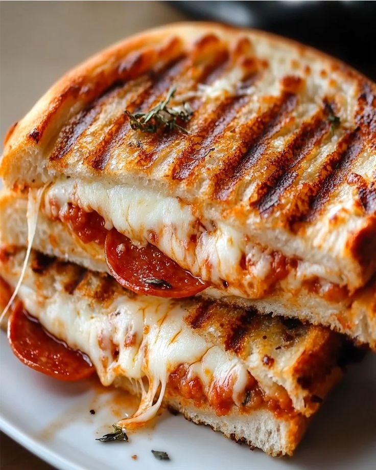 two grilled cheese sandwiches stacked on top of each other with pepperoni and mozzarella