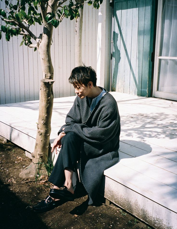 a man sitting on the ground next to a tree