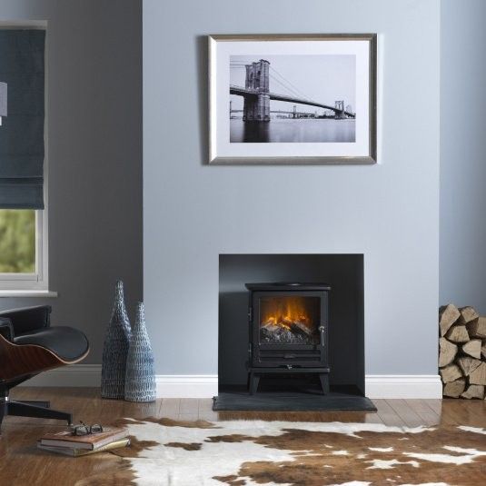 a living room with a fire place in the center and pictures on the wall above it