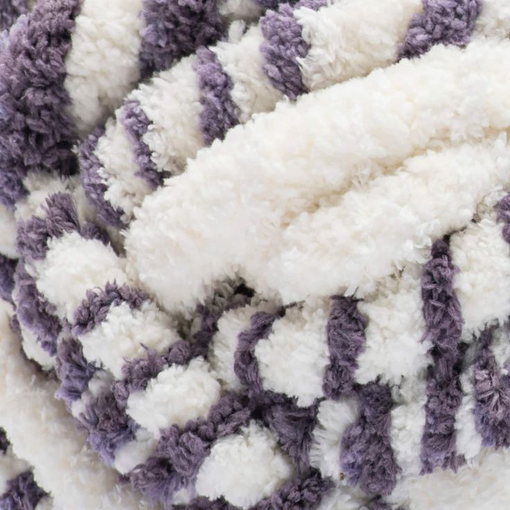 a pile of purple and white blankets laying on top of each other