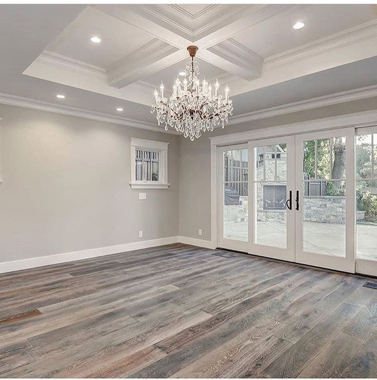 an empty living room with french doors and chandelier