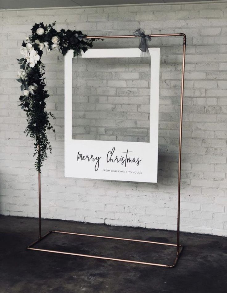 a sign that says merry christmas on it next to a chair and potted plant