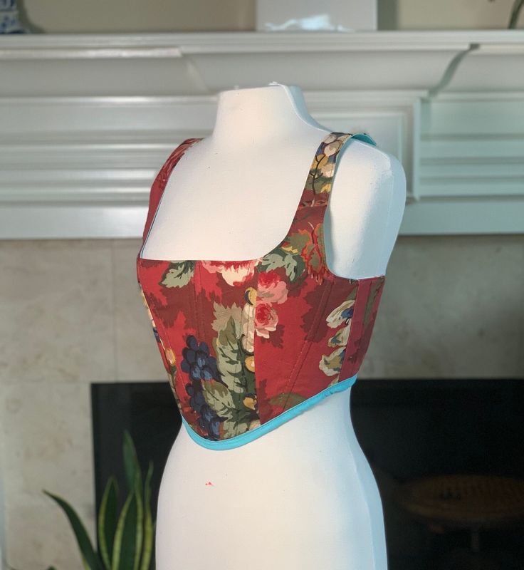 Over-bust corset with flexible boning and white lacing in back.  Made entirely of scrap fabrics. One side is a retro mid-century modern green and pink geometric design cotton, flanked by aquamarine and light blue floral cotton in back.  Other side is a rouge victorian floral fabric. US size small, 4-8 Sizing is pretty flexible because of lace-up closure. Message me if you have questions! Mannequin's measurements - Waist: 27" Bust: 37" I make custom order corsets as well, please contact me with questions! Spring Cotton Fitted Corset, Fitted Multicolor Sleeveless Corset, Fitted Green Corset For Spring, Spring Green Fitted Corset, Red Fitted Vintage Corset, Vintage Fitted Corset With Square Neck, Vintage Square Neck Fitted Corset, Floral Print Fitted Sleeveless Corset, Sleeveless Multicolor Summer Corset