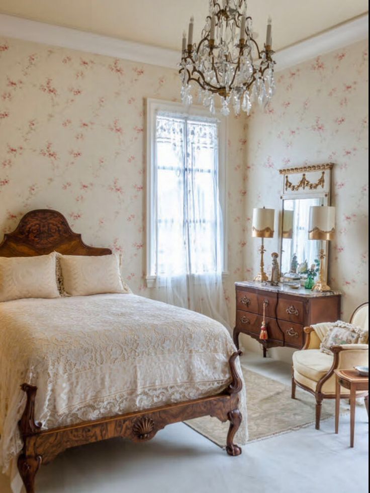 a bed sitting in a bedroom next to a window with a chandelier above it