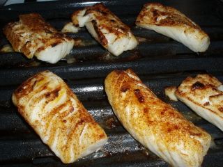 several pieces of fish are cooking on the grill