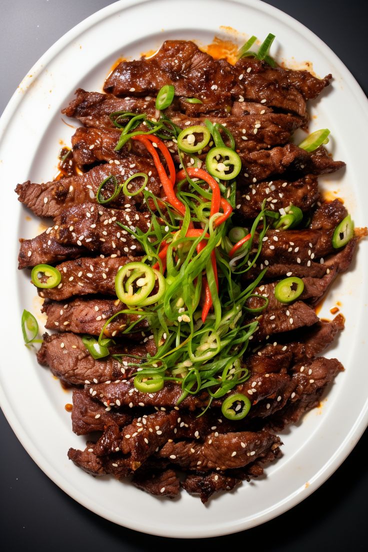 a white plate topped with meat and veggies covered in sesame seeds on top of a table