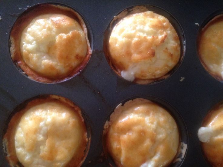 six muffins are sitting in a pan with some cheese on top and one has been baked