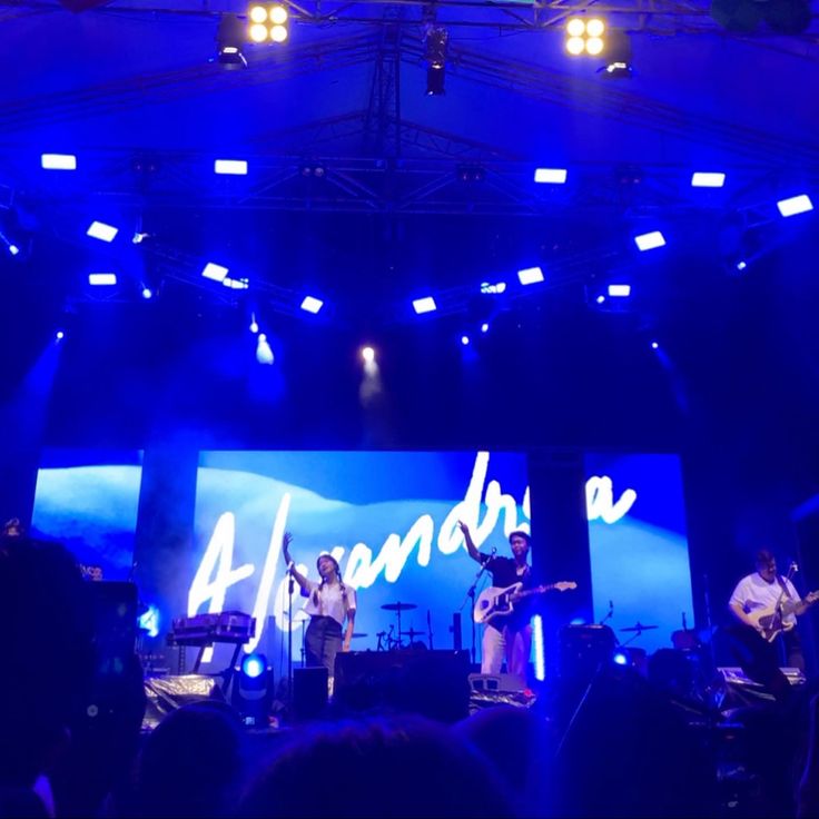 a band performing on stage in front of an audience at a concert with bright blue lights